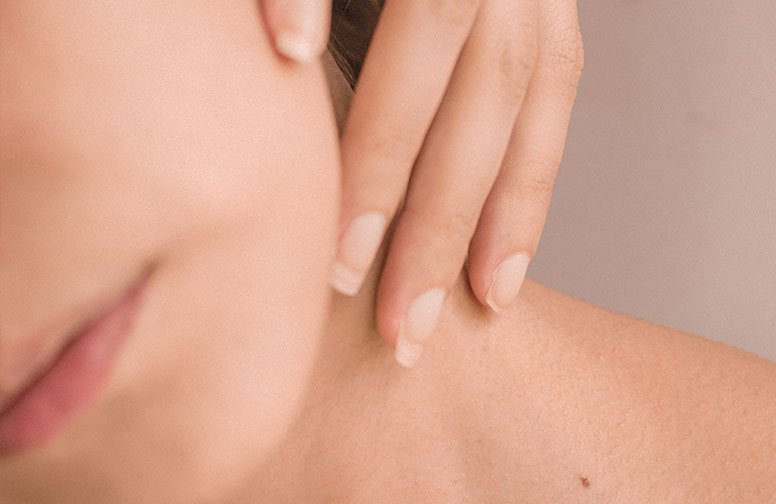 Nahaufnahme einer Person, die ihr Gesicht massiert, zur Veranschaulichung von Techniken zur Faltenreduzierung und Hautpflege.