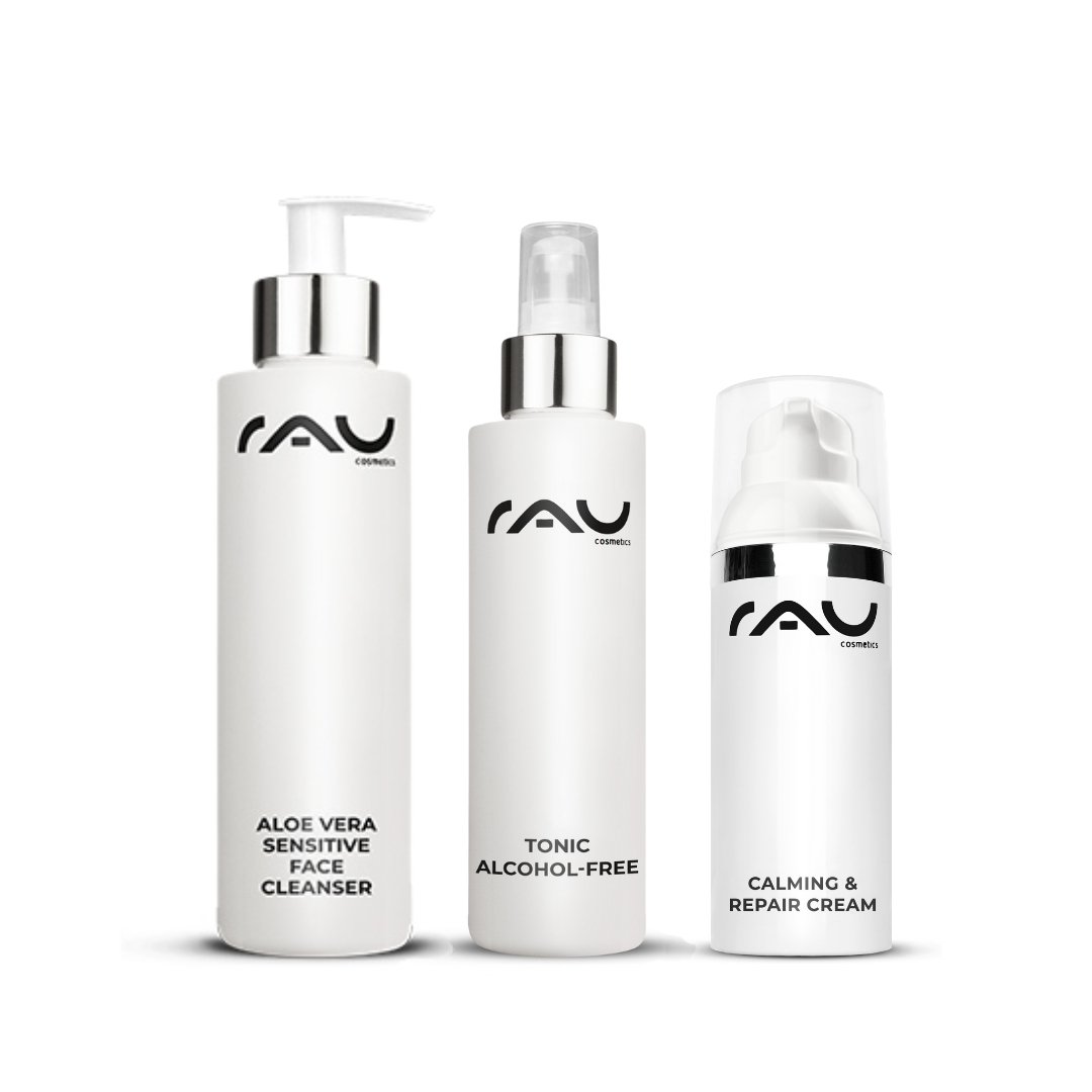Tre prodotti per la cura della pelle di RAU Cosmetics per pelli sensibili: Aloe Vera Sensitive Face Cleanser, tonico analcolico e Calming & Repair Cream, in eleganti flaconi bianchi con scritte chiare.