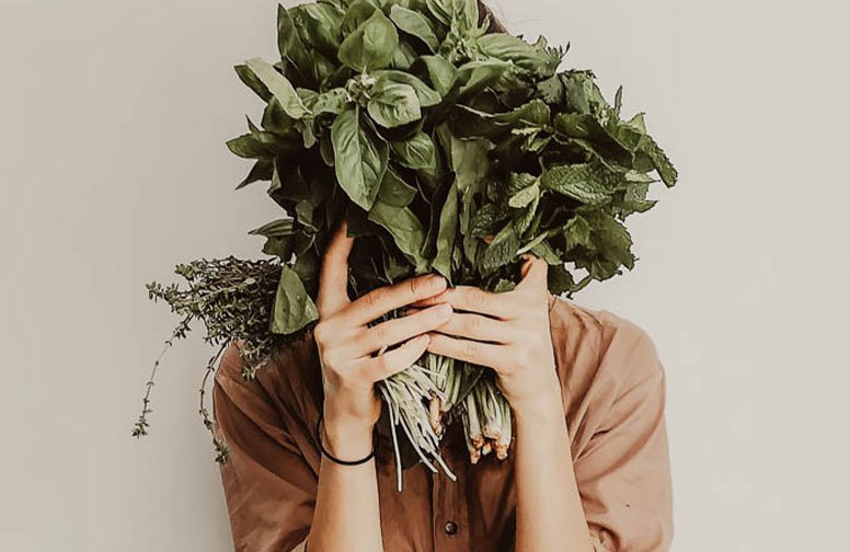Frau mit frischen Kräutern wie Basilikum, Minze und Thymian, die ihre Ernährung und Hautgesundheit symbolisiert.